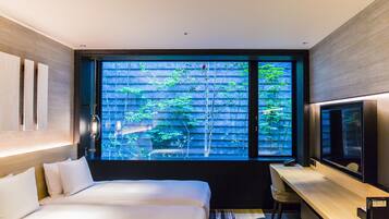 Una habitación de hotel moderna con un ventanal grande, una cama, un escritorio y un televisor.