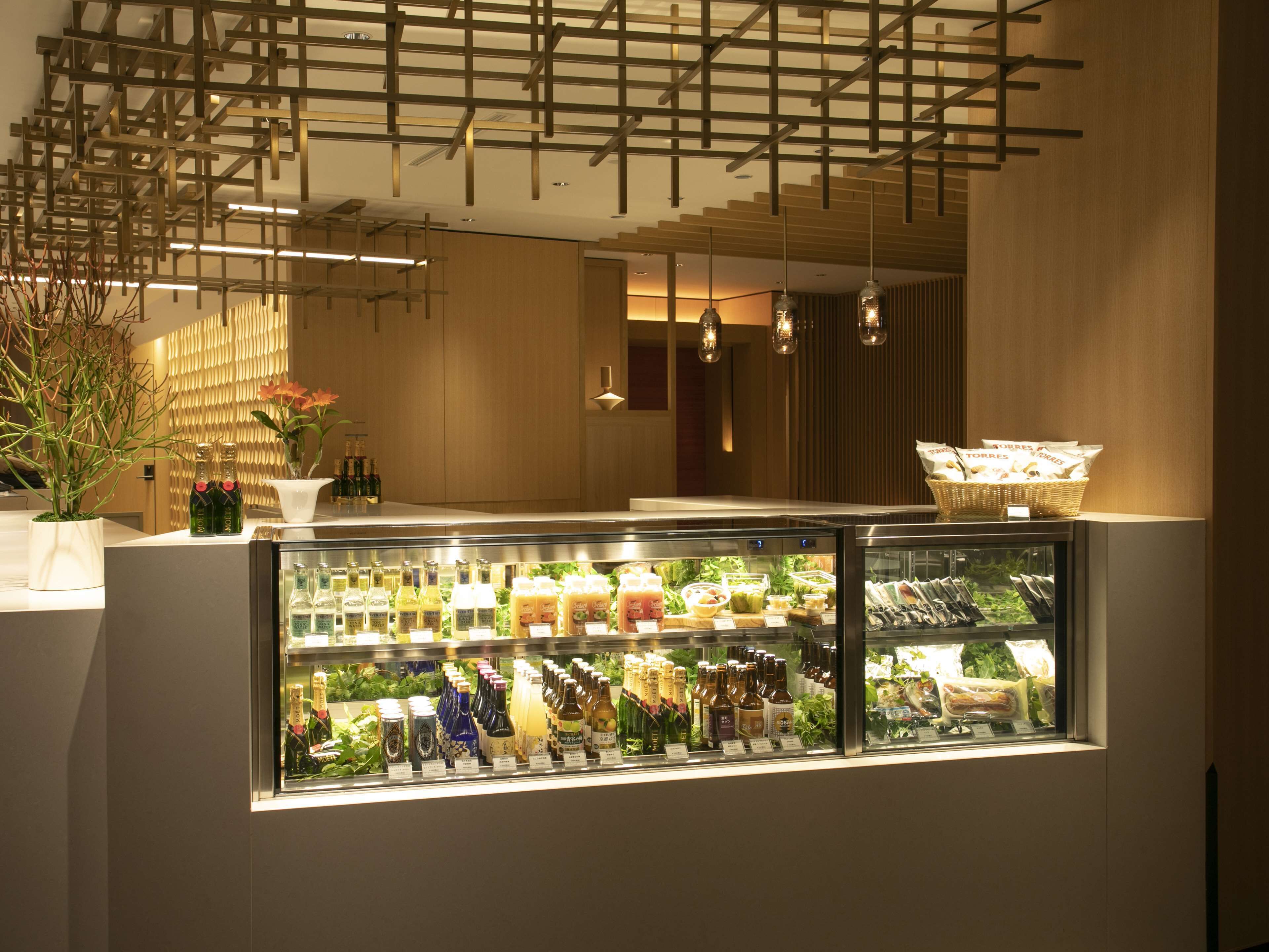 A modern hotel lobby with a glass display case filled with various beverages and snacks.