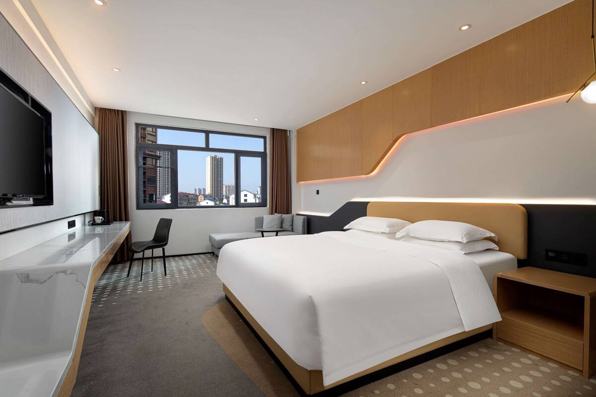 Une chambre d’hôtel moderne équipée d’un grand lit, d’un bureau, d’une chaise et d’un téléviseur.