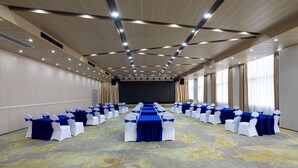 A conference room with rows of tables and chairs, a stage, and a patterned carpet. - Microtel by Wyndham Miluo Downtown Hotel (Yueyang)