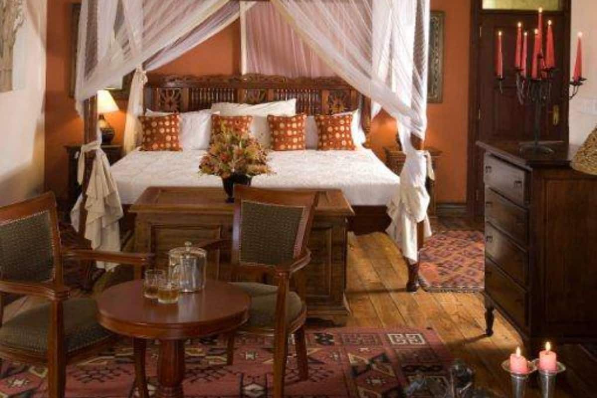 Une chambre à coucher avec un lit à baldaquin, une table en bois et une chaise.