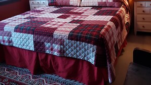 A bedroom with a wooden headboard, a red and white quilted bedspread, and a patterned rug. - LOVELY/CENTRALLY LOCATED/GROUND FLOOR APARTMENT (Warrensburg)