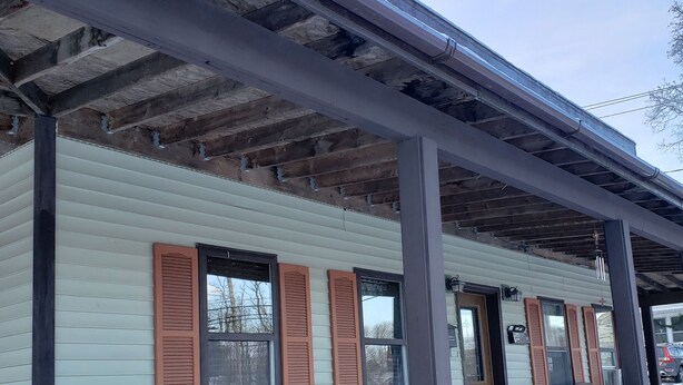 A covered porch with wooden chairs and a bench, a wooden deck, and a snow-covered ground. - LOVELY/CENTRALLY LOCATED/GROUND FLOOR APARTMENT (Warrensburg)