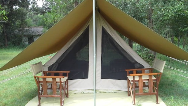 Uma tenda com duas cadeiras de madeira e uma mesa em frente.