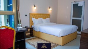 A hotel room with a bed, bedside tables, a chair, and a rug. - Hotel Taji (Nanyuki)