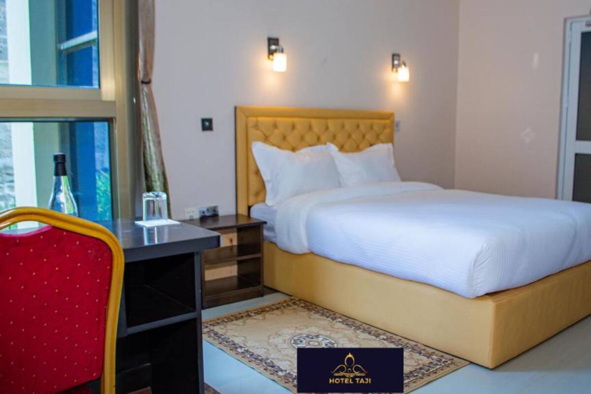 A hotel room with a bed, bedside tables, a chair, and a rug.