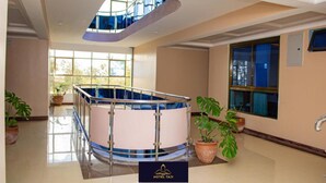 A spacious atrium with a central pool, large windows, and potted plants. - Hotel Taji (Nanyuki)