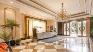 Un hall d’hôtel avec un comptoir d’accueil, un lustre et un sol à carreaux.