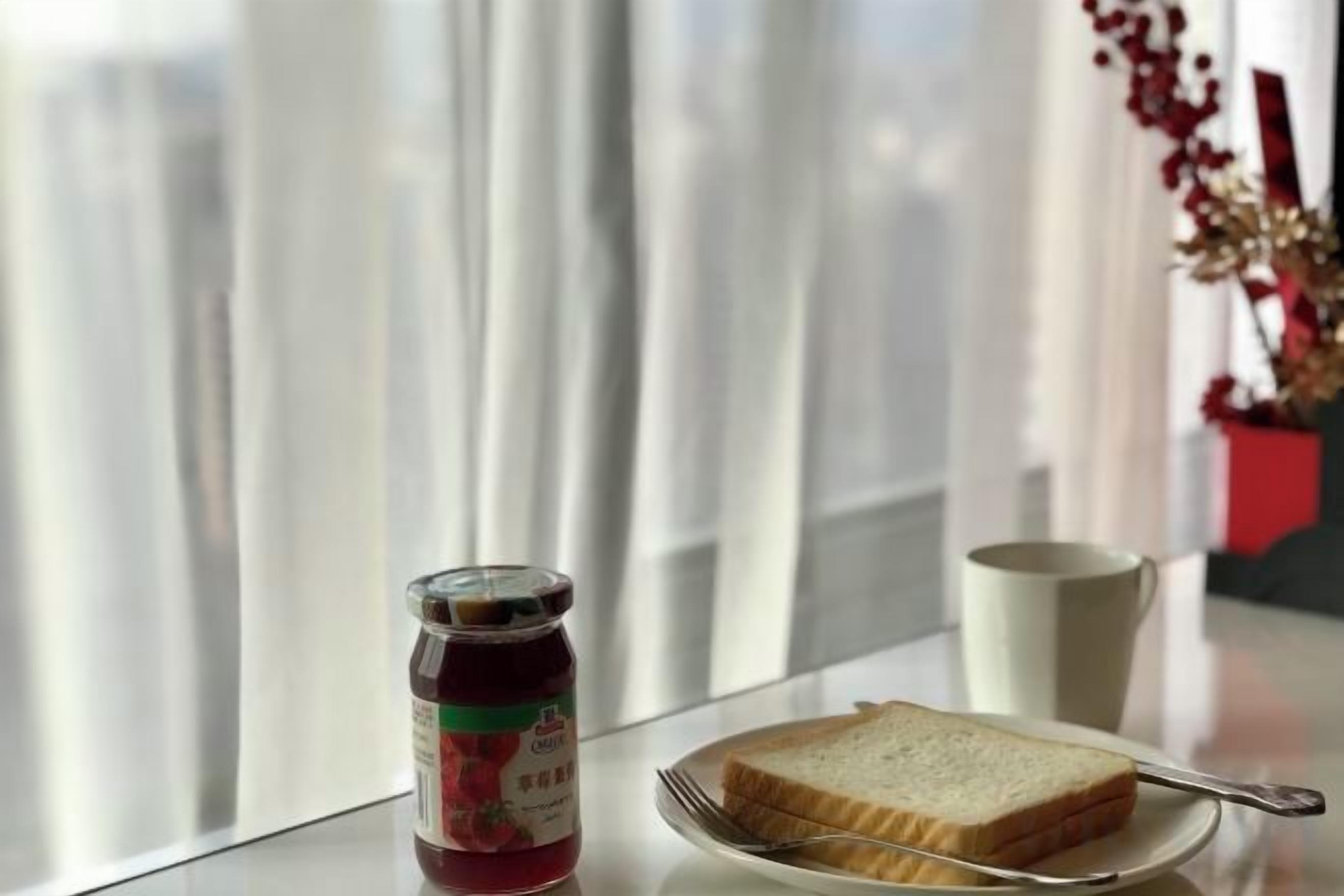 Une table avec un pot de confiture, une assiette avec une tranche de pain et une tasse.