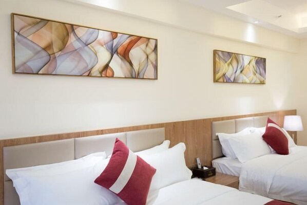 A hotel room with two beds, each with white bedding and red pillows. There are abstract paintings on the walls and a wooden headboard. - Marco Polo Hotel (Jiangmen Wanda Plaza) (Jiangmen)