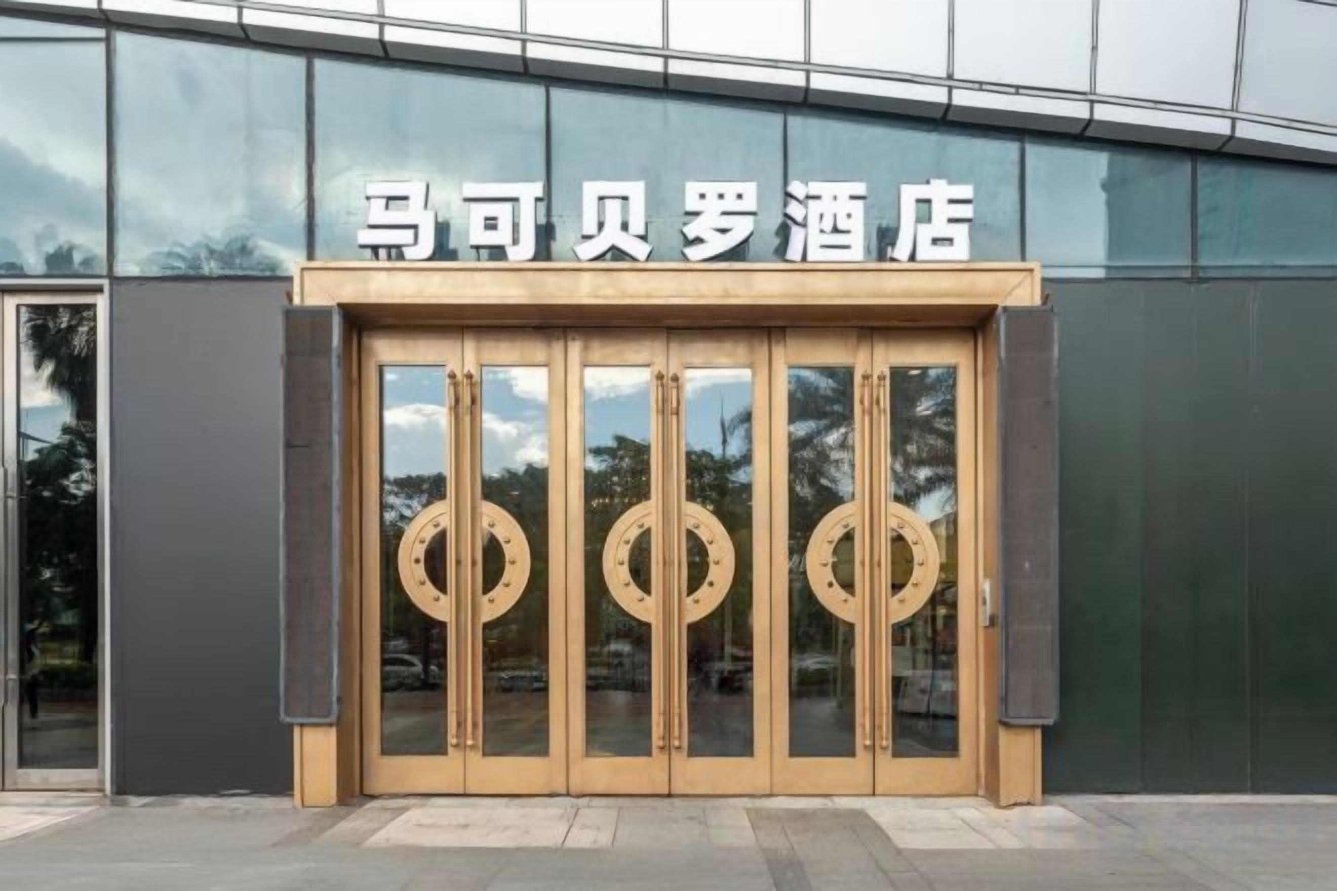A hotel entrance with a modern facade and a set of revolving wooden doors.