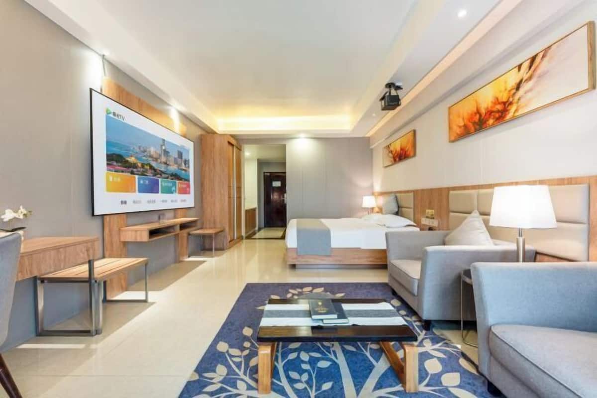 A hotel room with a bed, a sofa, a coffee table, a TV, and a desk.