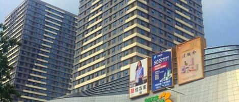 Il s'agit d'un bâtiment moderne à plusieurs étages, doté d'une façade incurvée en verre. On peut y voir plusieurs publicités sur la partie extérieure.