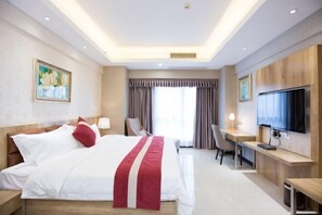 A hotel room with a bed, a desk, a chair, a TV, and a painting on the wall. - Marco Polo Hotel (Jiangmen Wanda Plaza) (Jiangmen)
