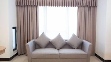 A room with a sofa, curtains, and a window.