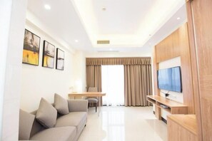 A modern living room with a sofa, a TV, a dining table, and a large window with curtains. - Marco Polo Hotel (Jiangmen Wanda Plaza) (Jiangmen)