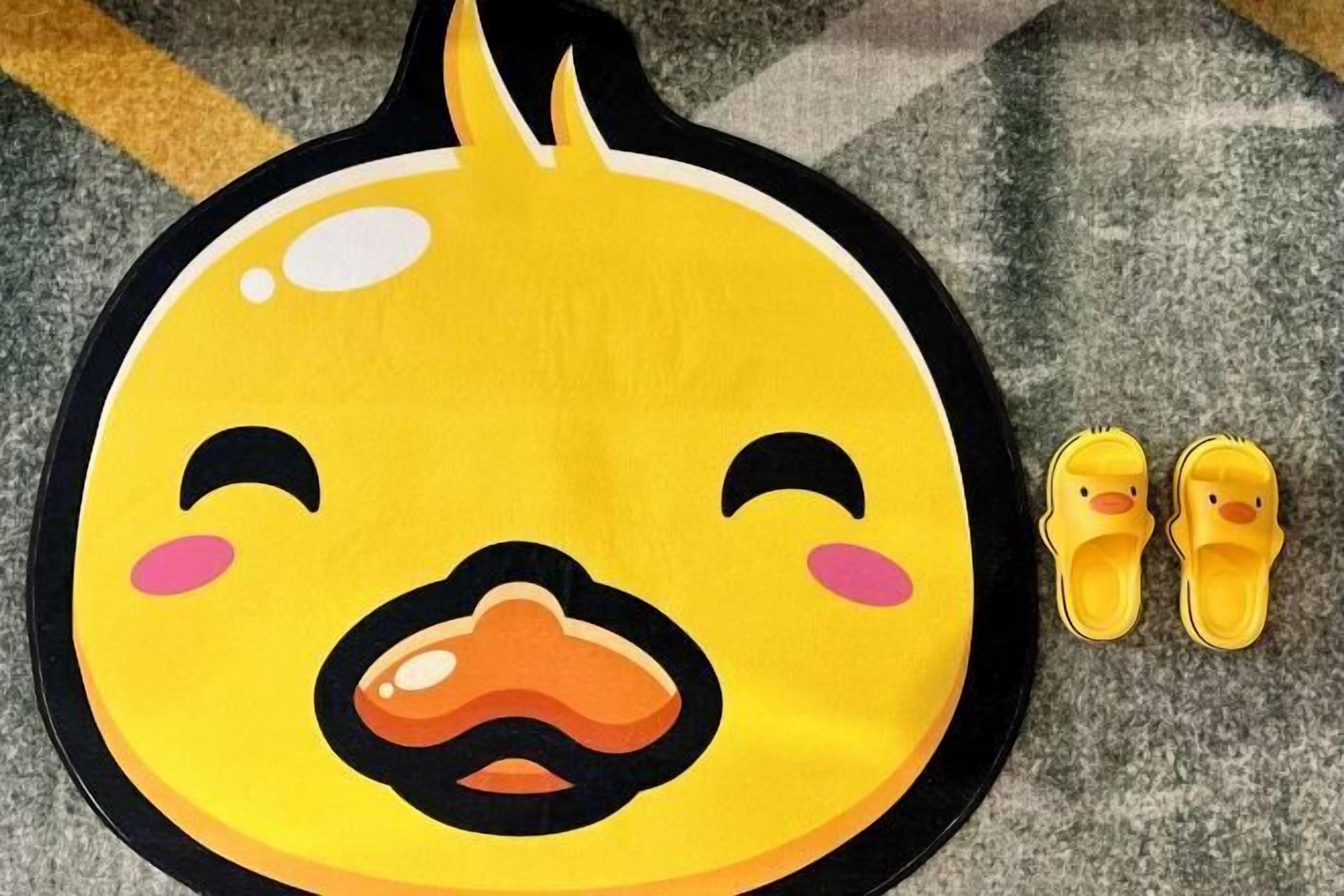 A yellow duck-shaped mat with a pair of yellow slippers beside it.
