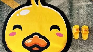 A yellow duck-shaped mat with a pair of yellow slippers beside it.