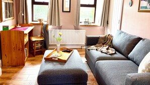A cozy living room with a grey sofa, wooden desk, and a radiator.