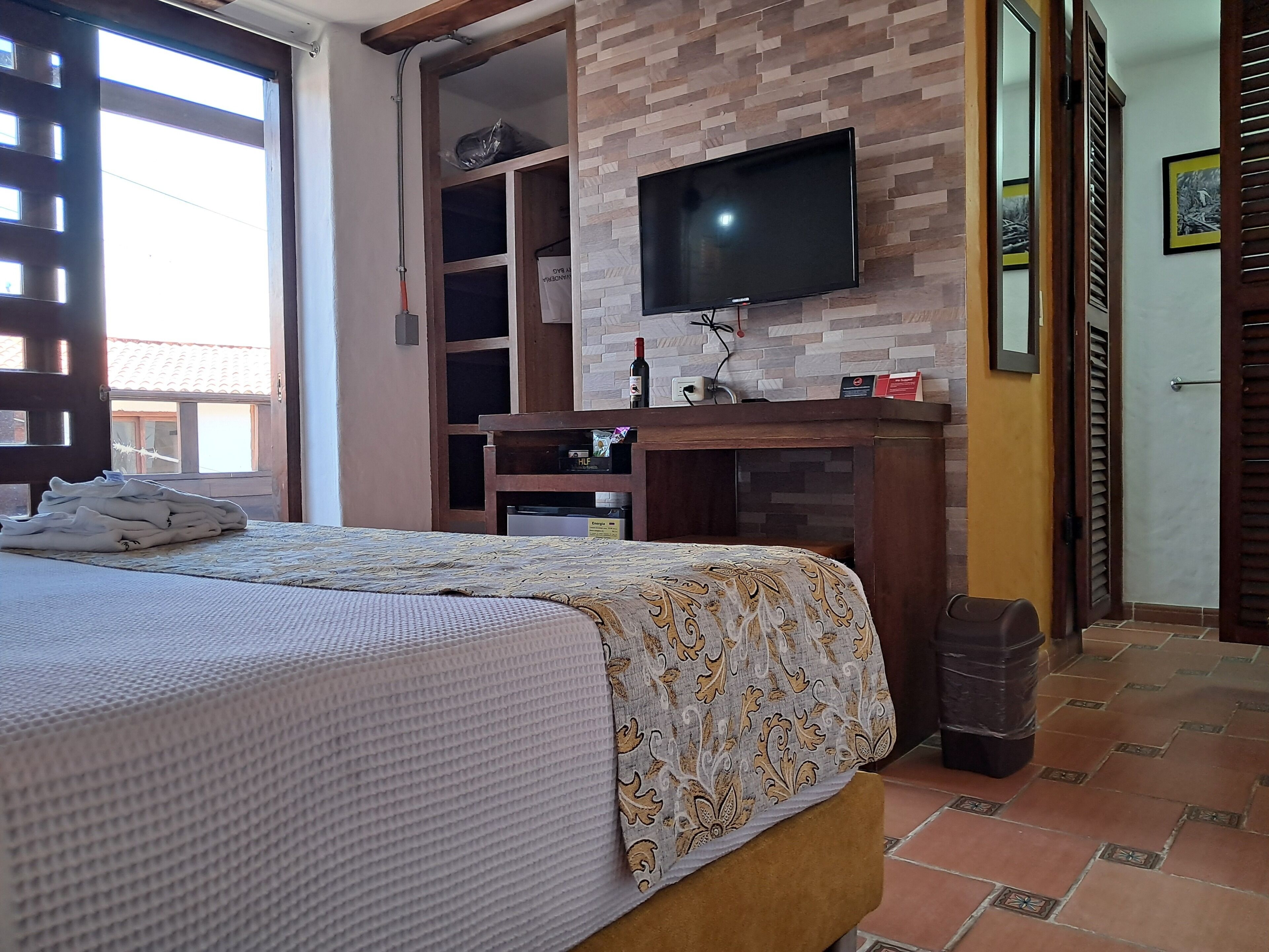 Une chambre d’hôtel avec un lit, un bureau, une télévision et une fenêtre.