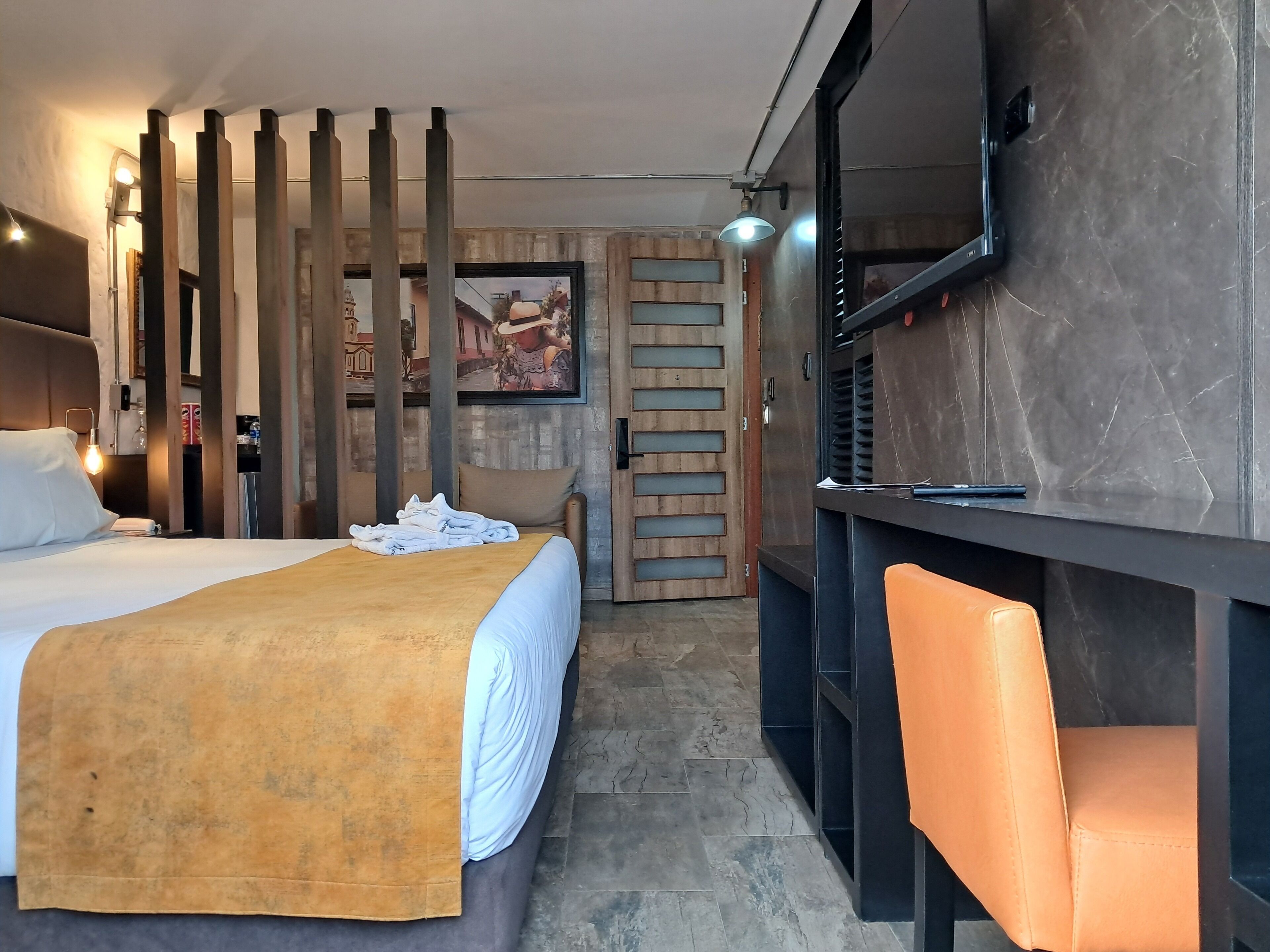 Una habitación de hotel con cama, escritorio, silla y un espejo grande.