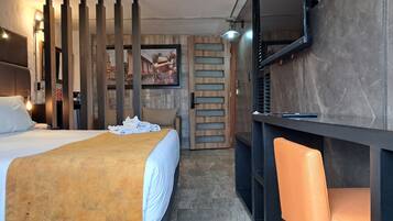 Una habitación de hotel con cama, escritorio, silla y un espejo grande.