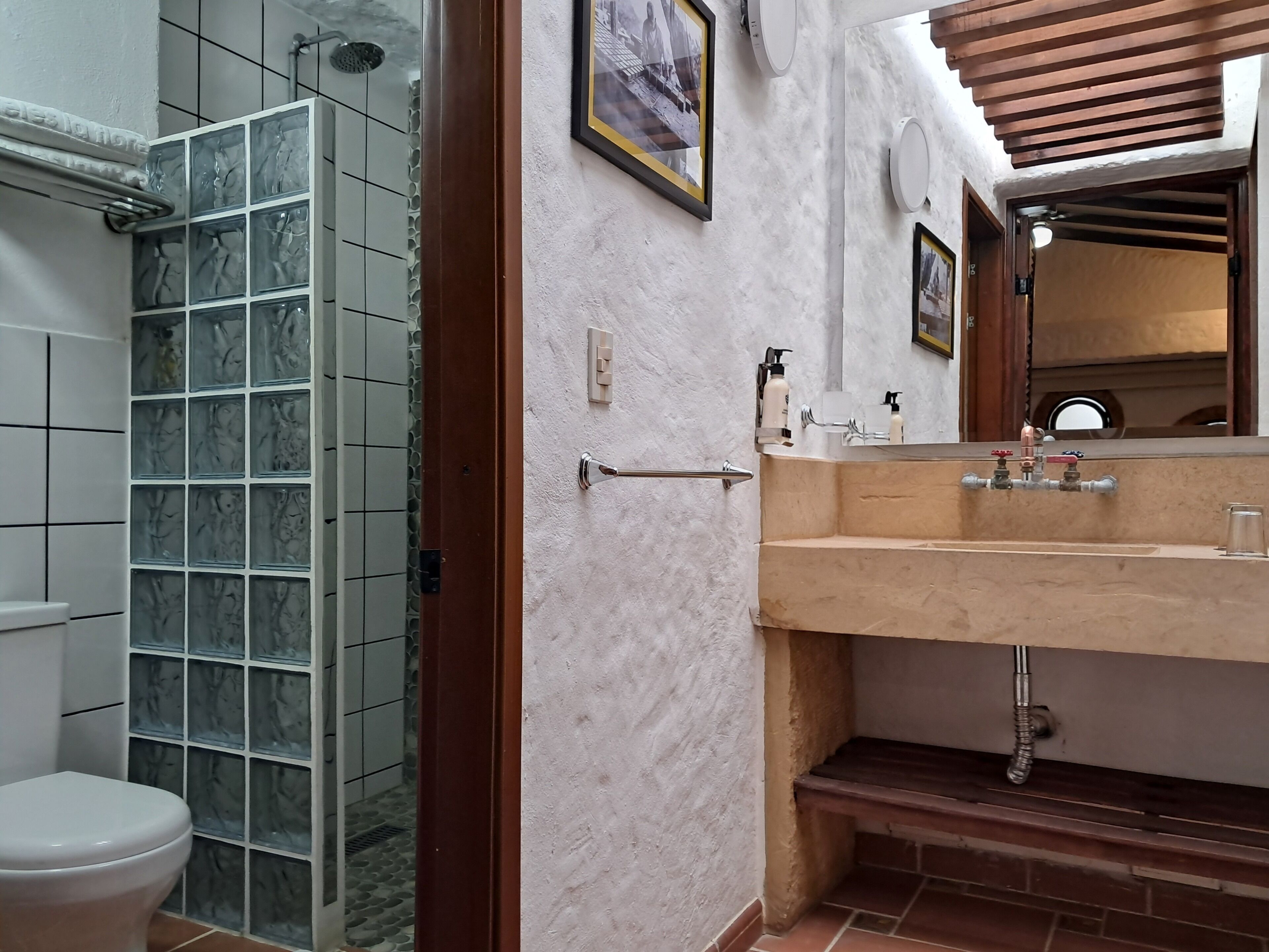 Un baño con cabina de ducha de vidrio, un lavamanos con espejo y un inodoro.