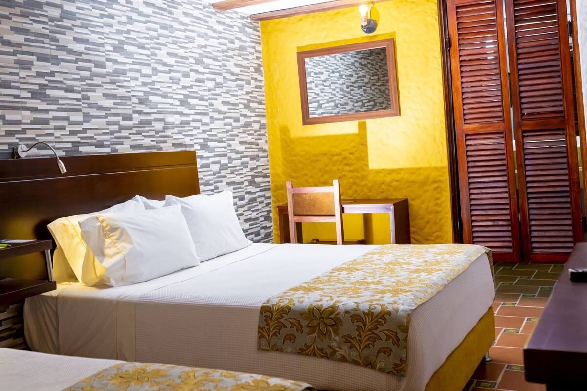 Una habitación de hotel con cama, mesita de noche, lámpara y una silla.