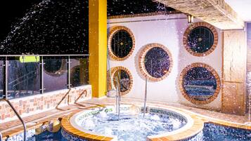 A hot tub with a tiled edge, surrounded by a brick wall with circular windows.