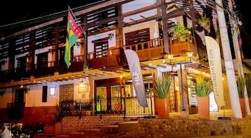 Un hotel con balcón, una bandera y un cartel.