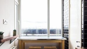 Una cocina con ventana, taburetes de madera, una encimera y una planta en maceta.