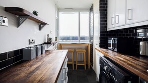 Una cocina moderna con encimera de madera, electrodomésticos negros y ventana con vistas a la ciudad.