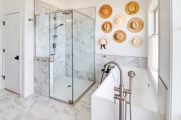 Une salle de bain moderne avec une douche à parois de verre, une baignoire blanche et un sol en marbre.
