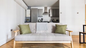 A modern living room with a grey sofa, green cushions, and a wooden coffee table. - The Dalston Apartments (London)