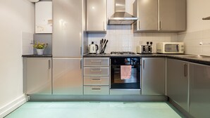 A modern kitchen with stainless steel appliances, a built-in oven, and a microwave. - The Dalston Apartments (London)