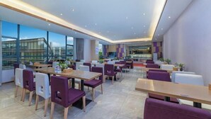A modern dining area with tables and chairs, large windows, and a view of buildings. - Lavande Hotel (Shenzhen Airport Fuyong Metro Station) (Shenzhen)
