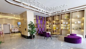 A modern hotel lobby with a clean, polished floor, purple seating, and a variety of displayed items on shelves. - Lavande Hotel (Shenzhen Airport Fuyong Metro Station) (Shenzhen)