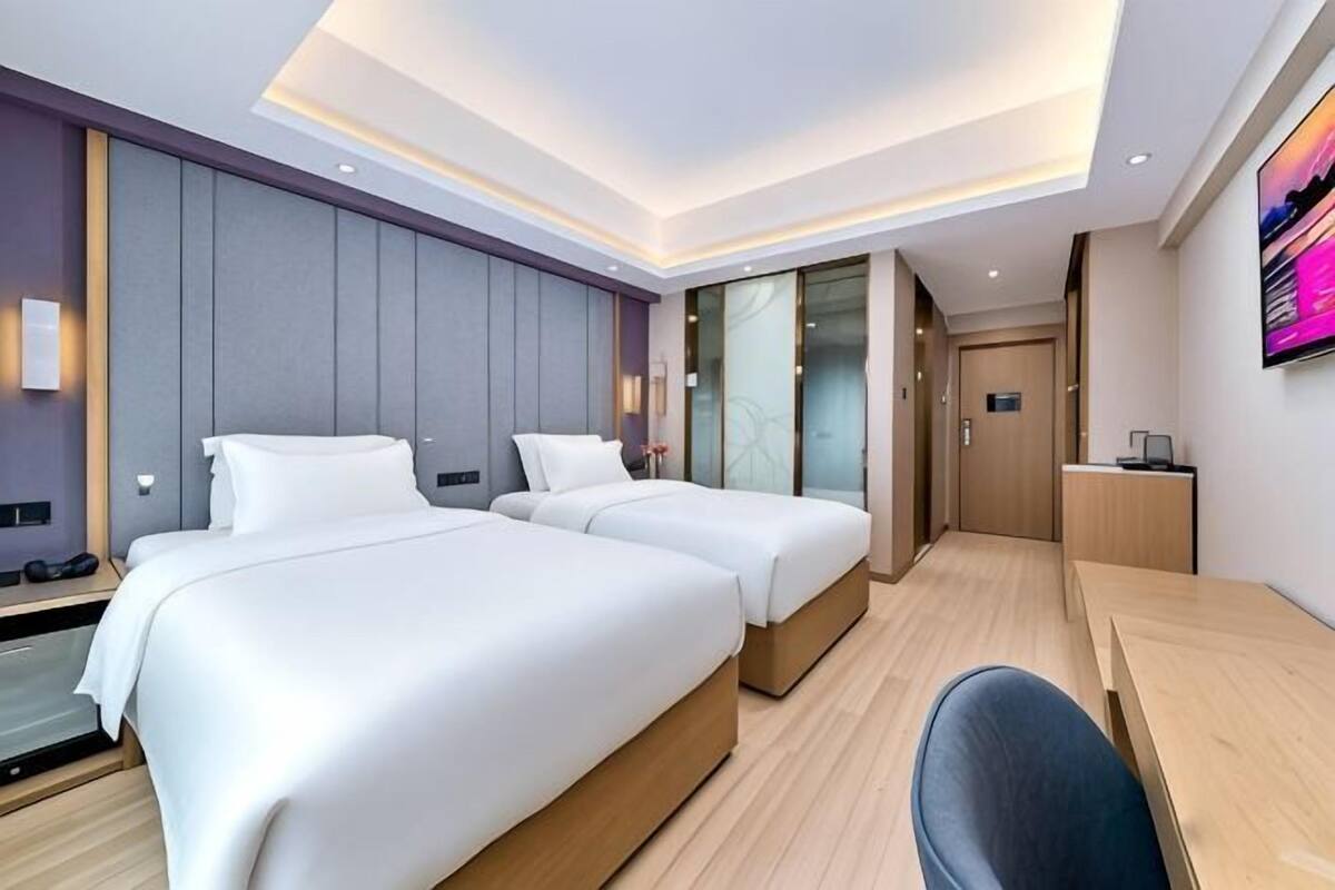 A hotel room with two beds, a desk, and a TV.