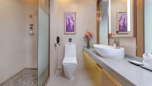 A modern bathroom with a glass shower enclosure, a white toilet, a sink with a large mirror, and two framed pictures on the wall. - Lavande Hotel (Shenzhen Airport Fuyong Metro Station) (Shenzhen)