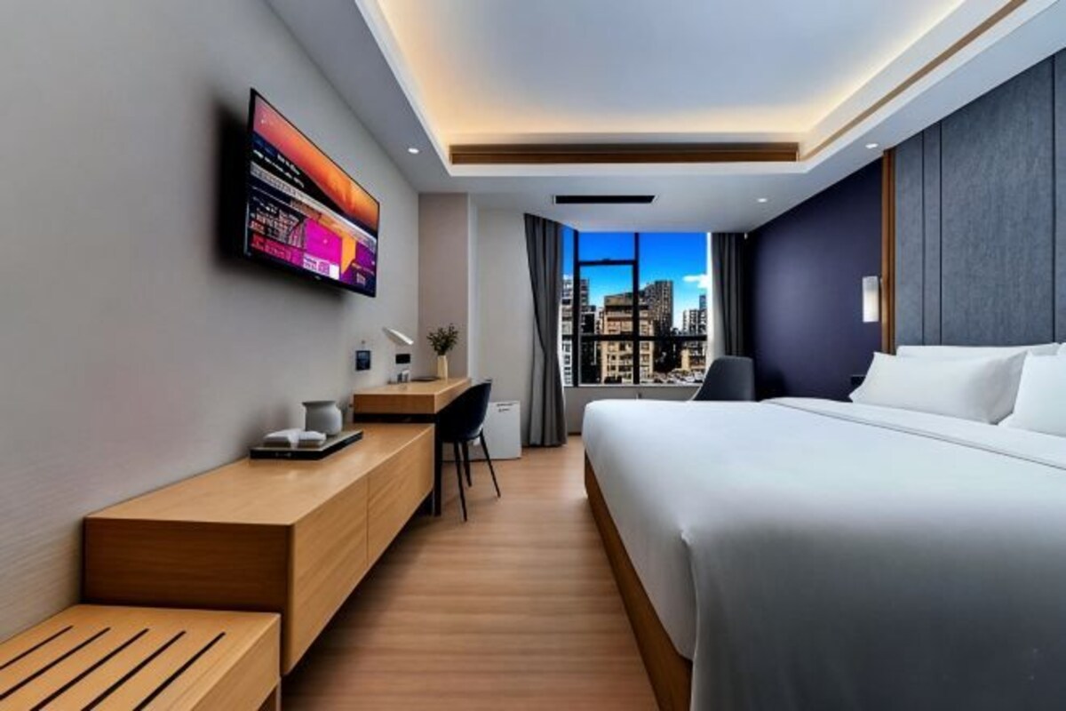 A modern hotel room with a bed, desk, and a city view.