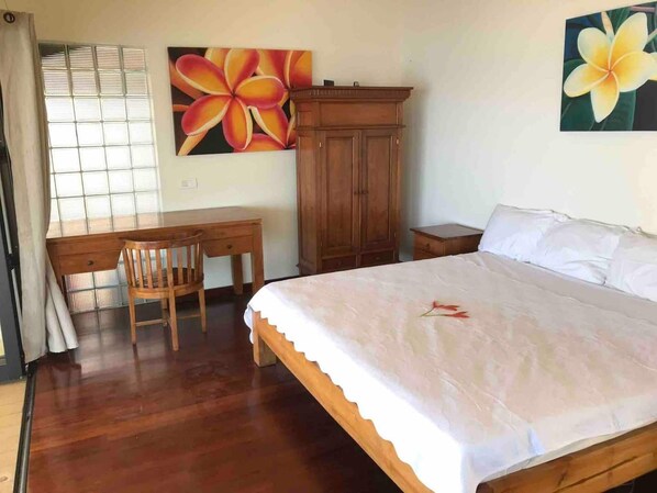 A bedroom with a wooden bed, a desk, a chair, a wardrobe, and a window with blinds. - Ocean Front Bungalow (Tumaraa)