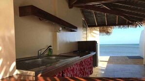 Una cocina con vista al mar, techo de paja y encimera de madera.