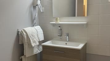 A modern bathroom with a white sink, a mirror, a towel rack, and a hairdryer.