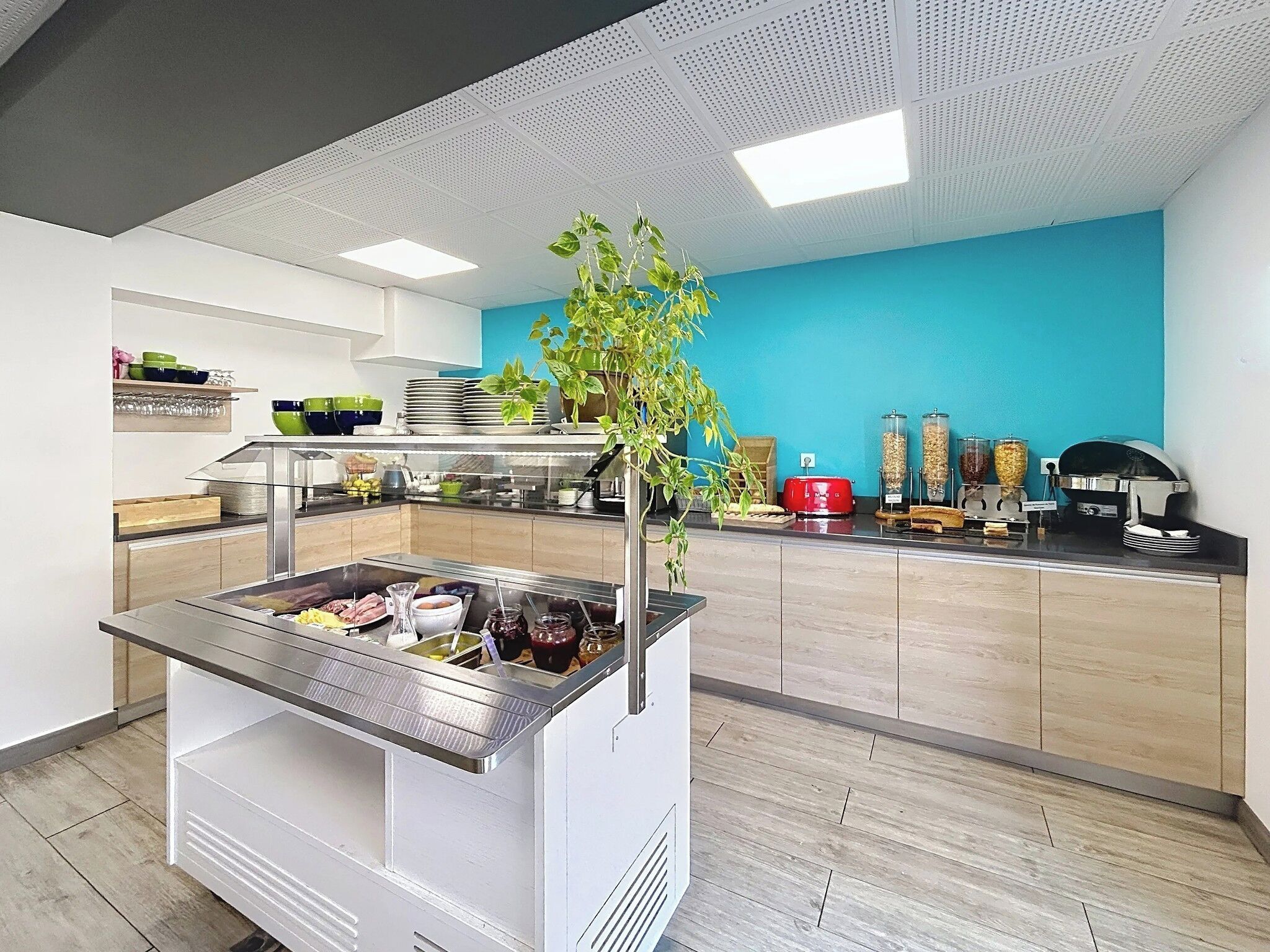 A modern kitchen area with a buffet setup, including a food display and various kitchen appliances.