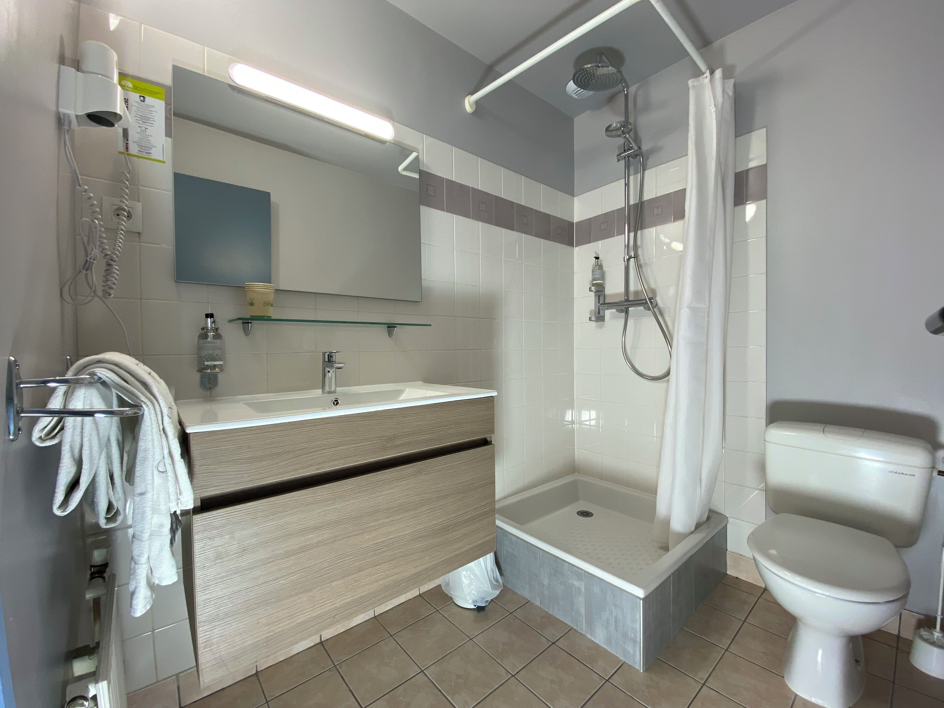 Une salle de bain moderne équipée d’une douche, de toilettes et d’un meuble-lavabo.