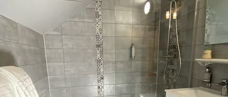 A modern bathroom with a shower, a vanity, and a patterned tile border.