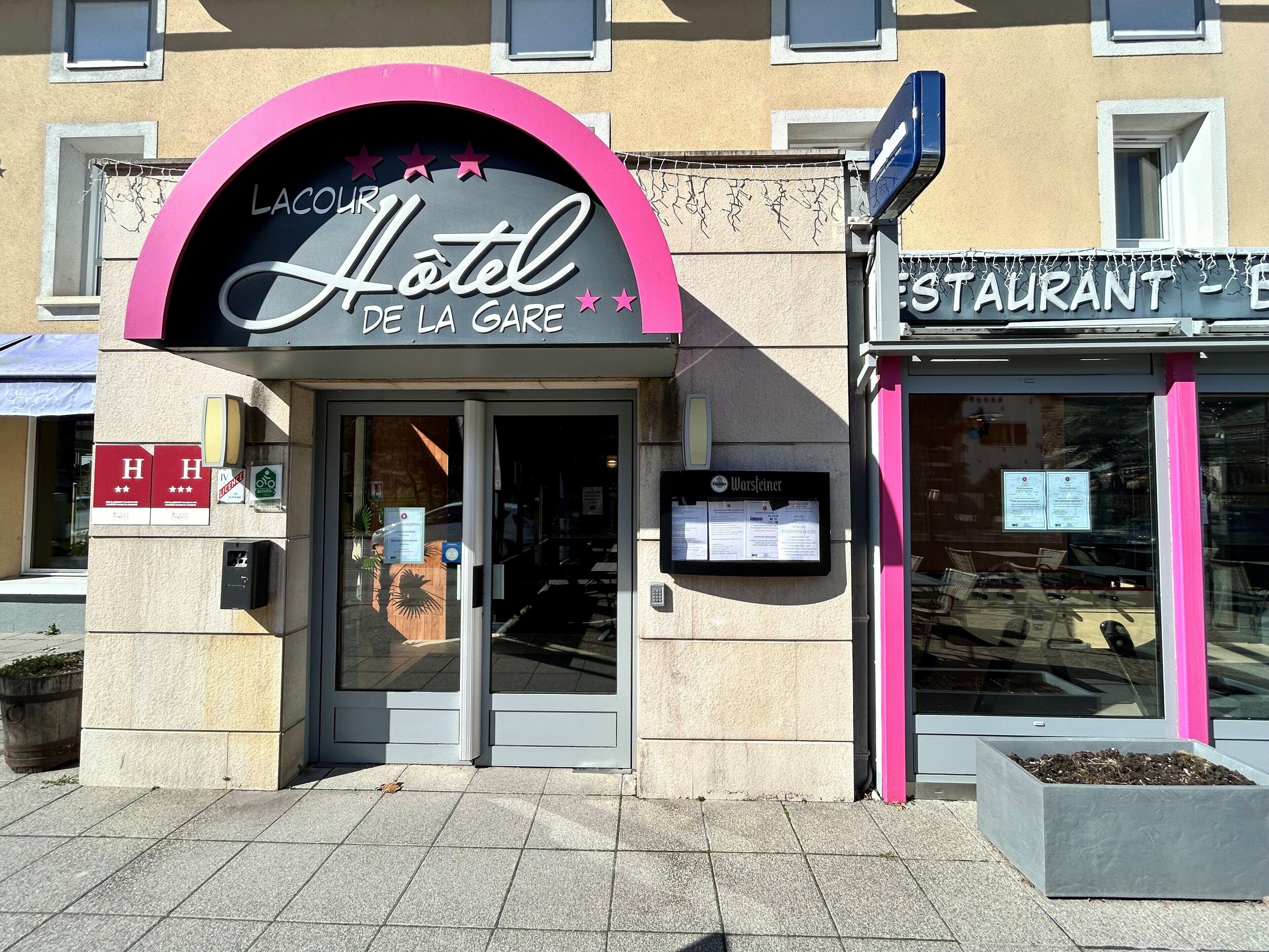 A hotel entrance with a pink arch and a sign for 'Hotel de la Gare'.
