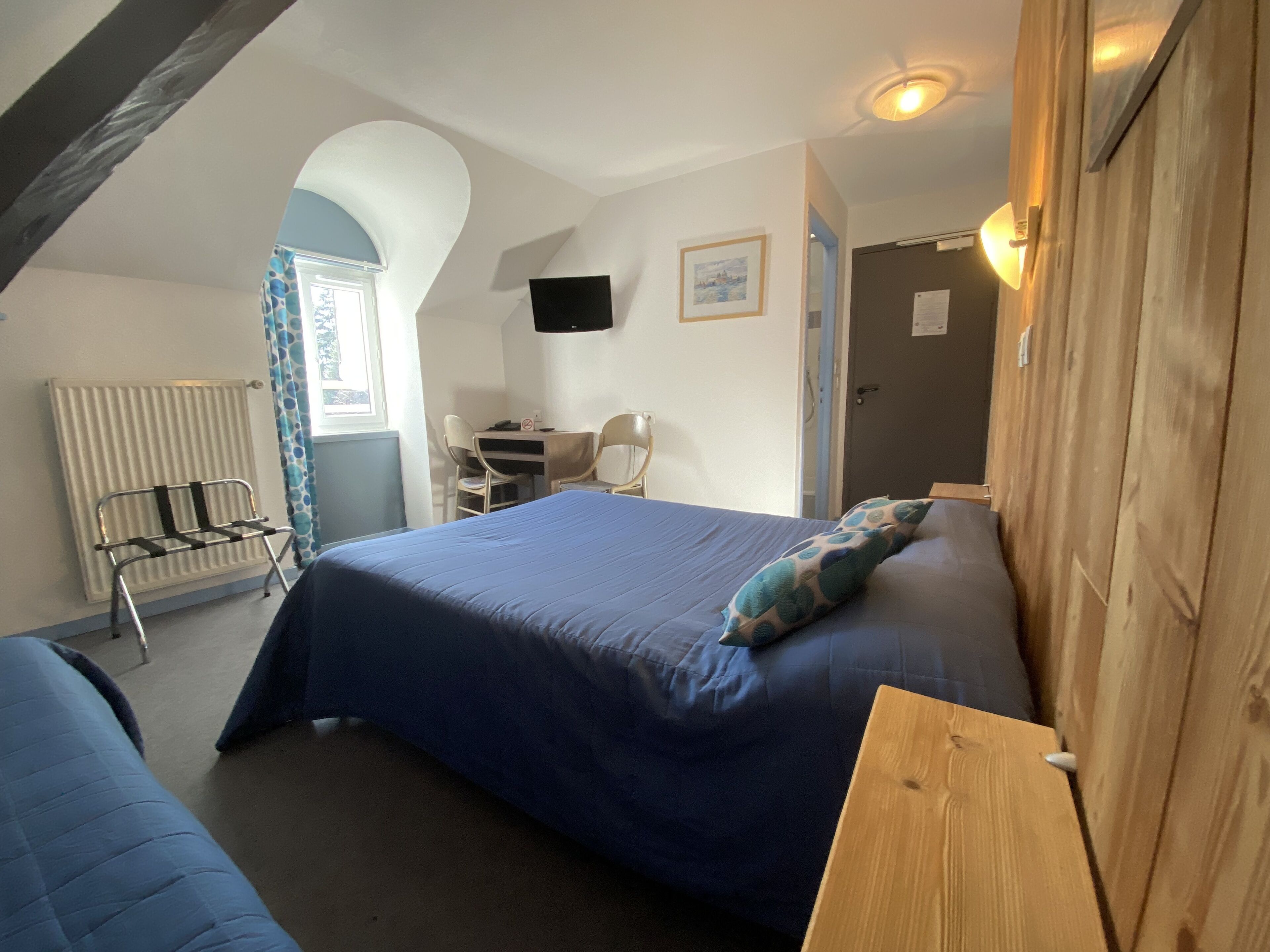 A bedroom with a bed, a desk, and a chair.