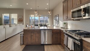 A modern kitchen with wooden cabinets, stainless steel appliances, and pendant lighting.