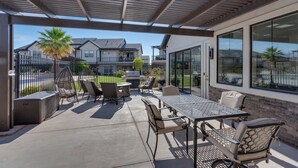 A covered patio with outdoor furniture, a grill, and a view of neighboring houses.